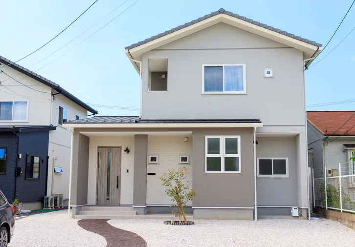 青空の下のグレーの2階建て住宅の外観