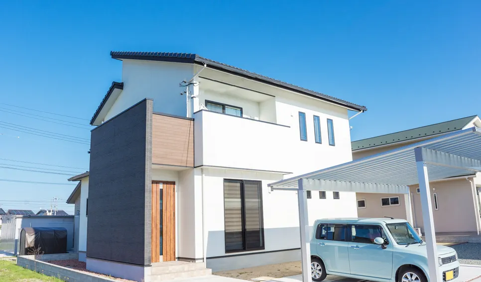 青空の下の白い2階建て住宅とカーポート